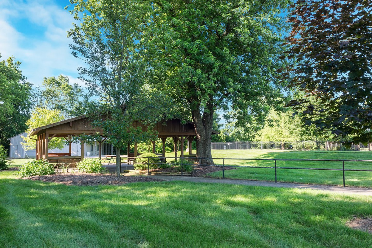 A peaceful park setting featuring a pavilion surrounded by lush green grass and trees.