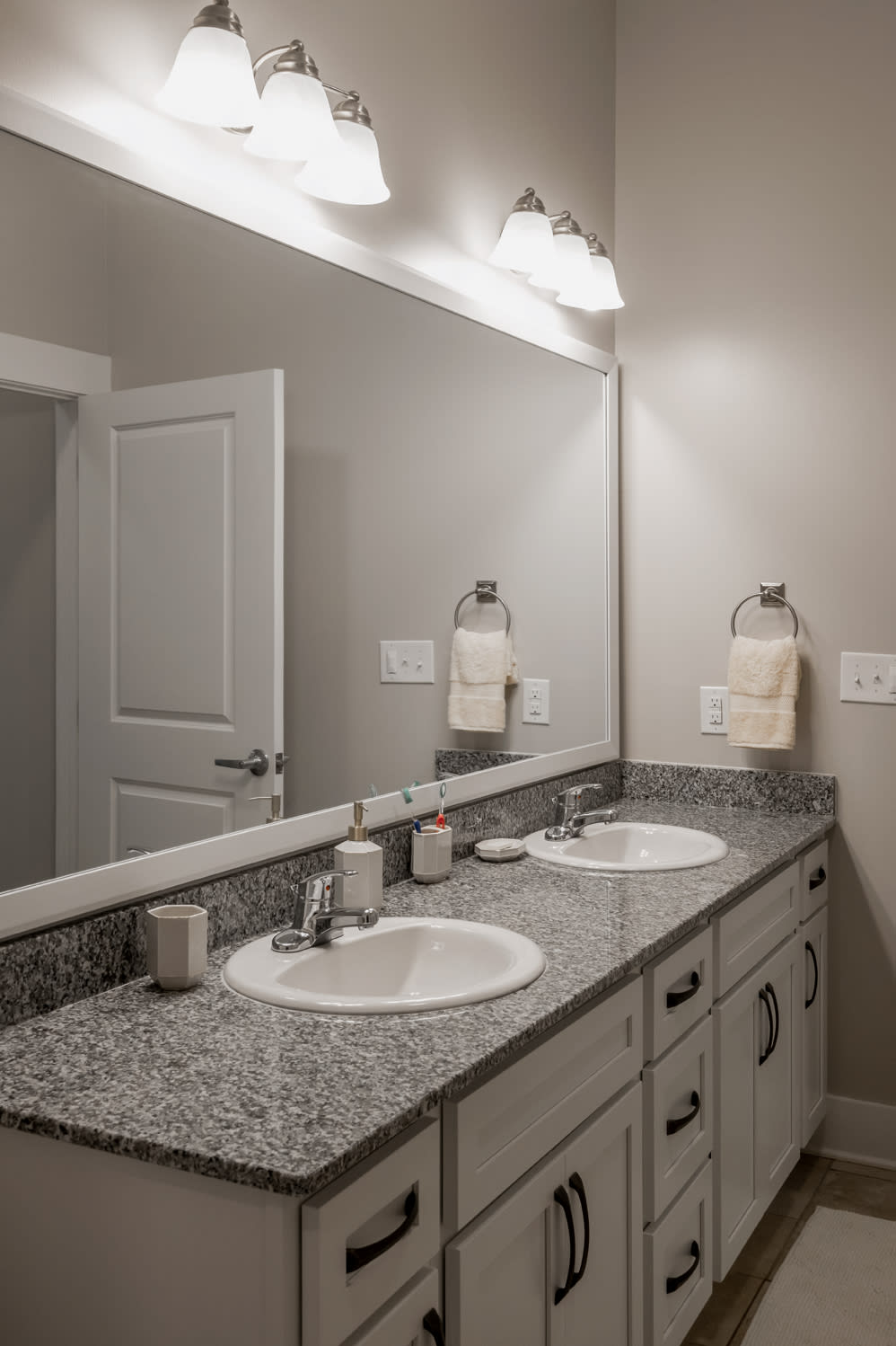 A modern bathroom with a double sink and granite countertops.