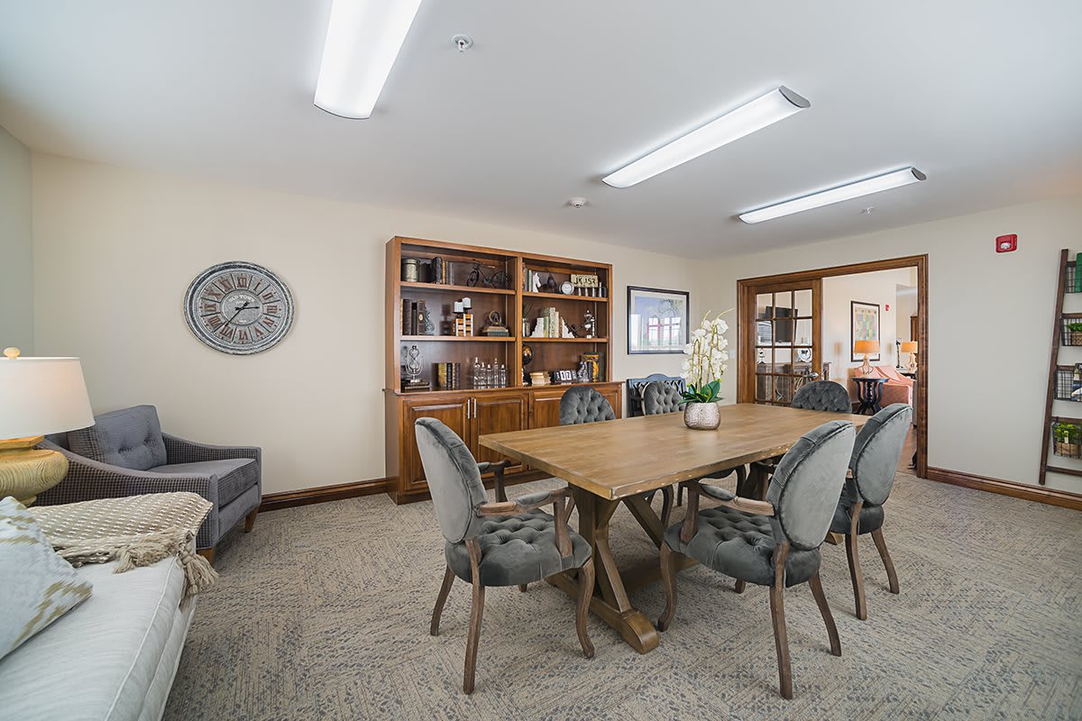 A well-furnished conference room with a large table, surrounded by chairs and bookshelves in the background.