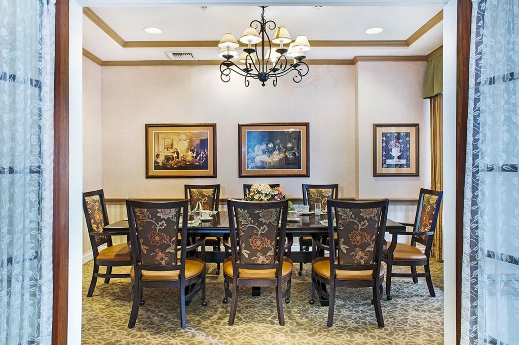 Elegant dining room with a large table, ornate chairs, and decorative paintings.