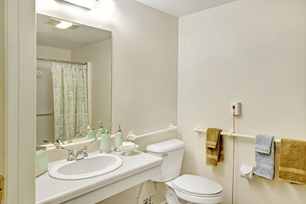 A clean and simple bathroom with a sink, toilet, and shower area.