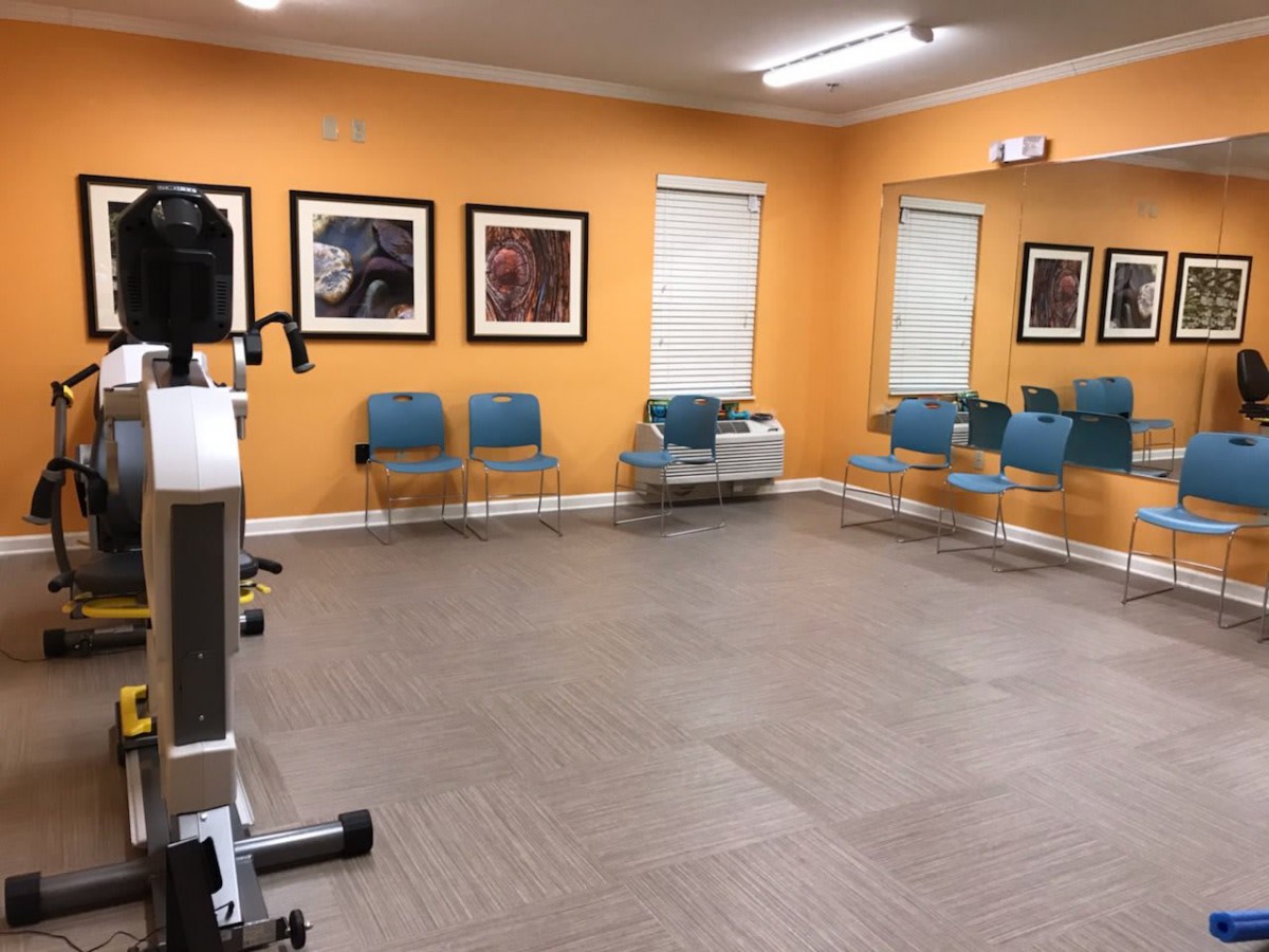An empty waiting room with orange walls, modern chairs, and artwork on the walls.