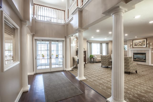A modern interior foyer with elegant columns leading into a spacious living room filled with natural light.