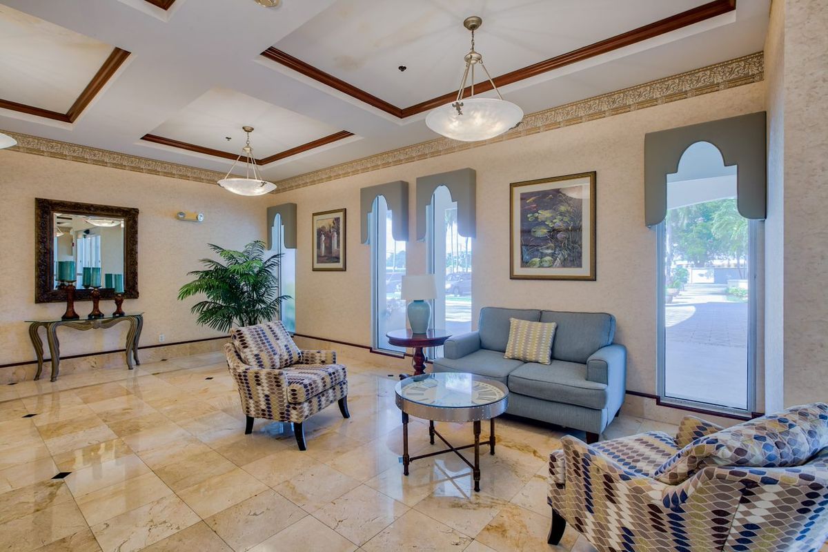 A well-lit lobby area featuring comfortable seating, decorative artwork, and large windows.