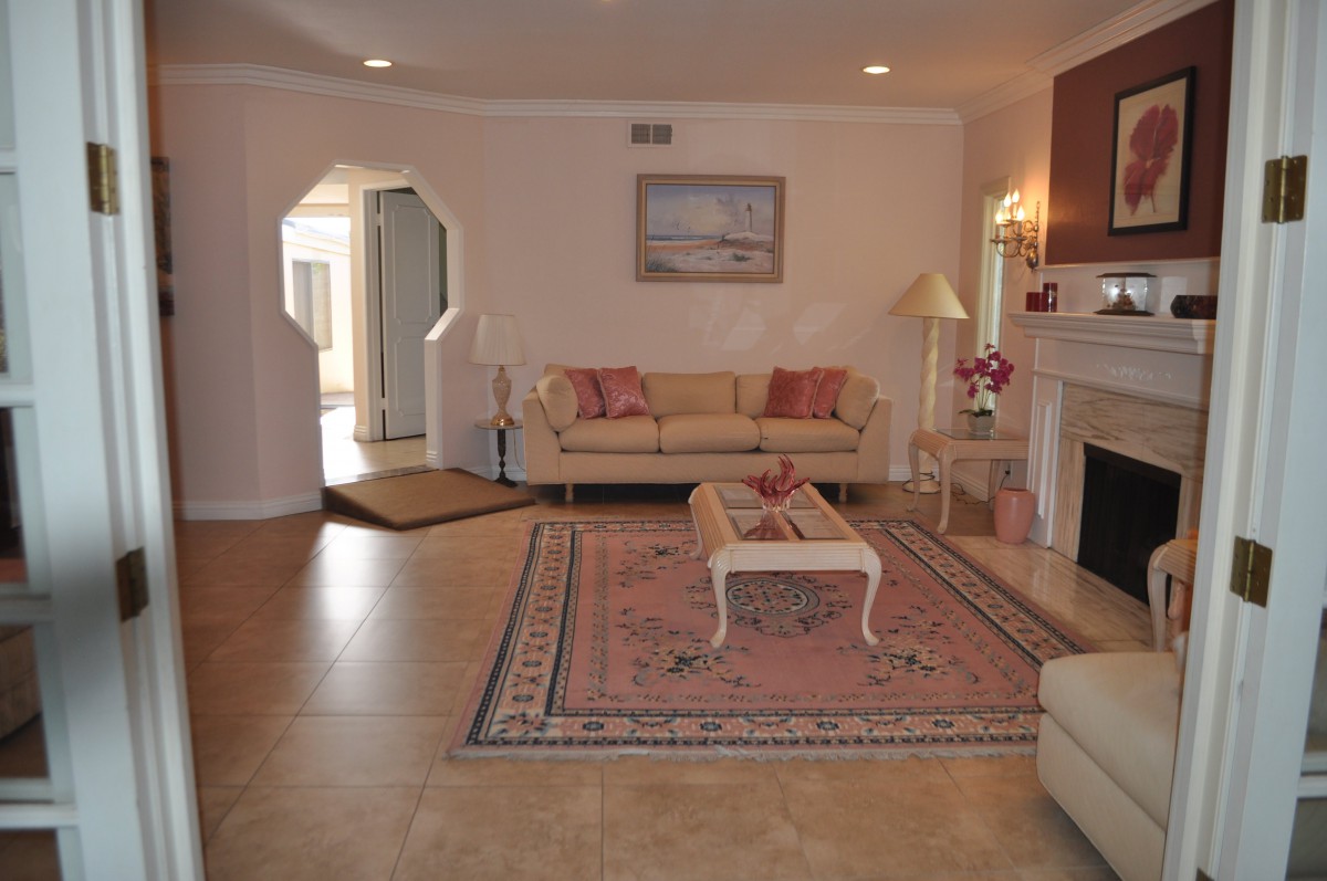 A cozy living room with sofas, a coffee table, and a fireplace, featuring elegant decor and soft lighting.