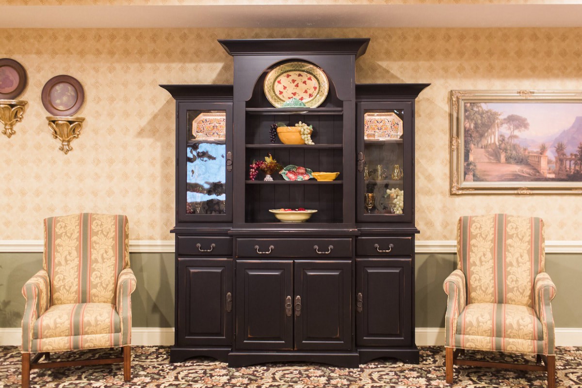 A traditional dark wooden cabinet with decorative plates displayed on the shelves.