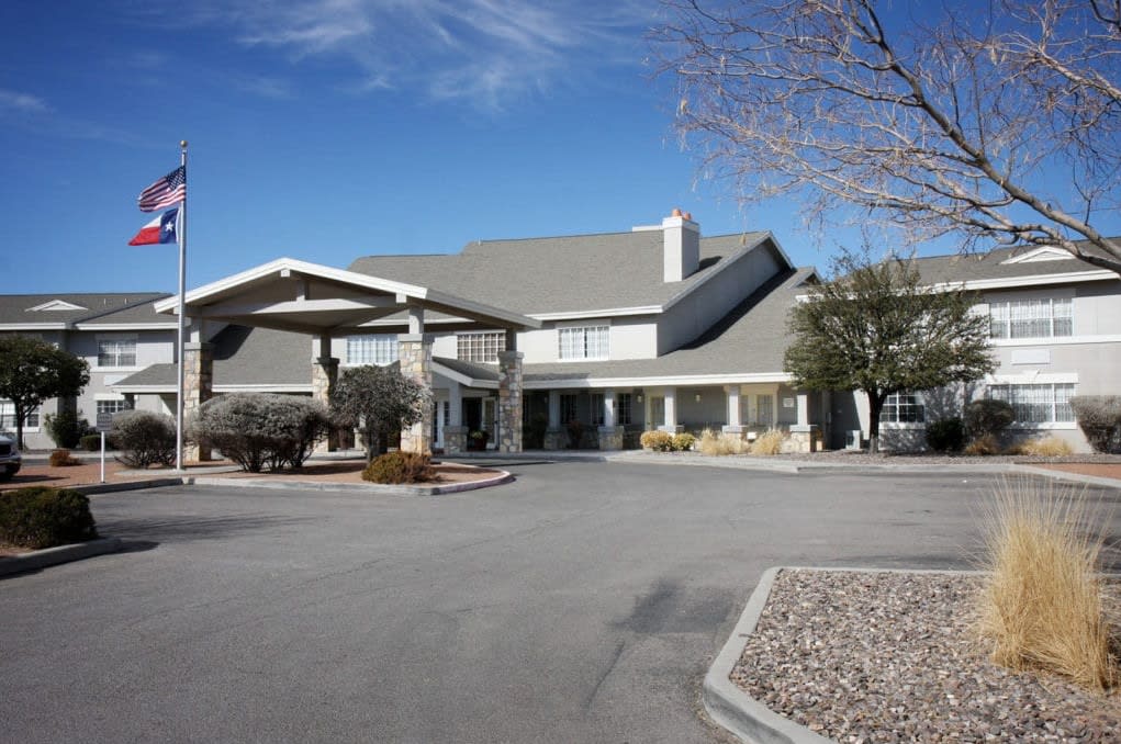 A hotel entrance with a driveway under a clear blue sky.