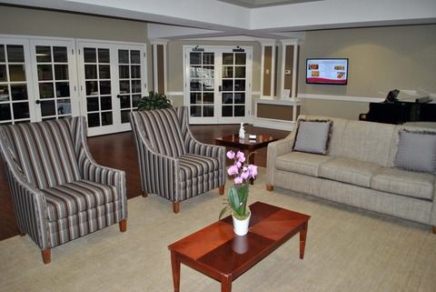 A cozy living room with striped armchairs, a sofa, and a coffee table adorned with a vase of flowers.