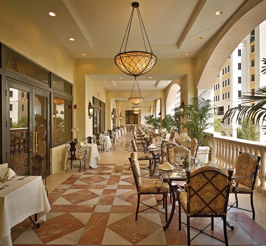 Elegant outdoor dining area with chandeliers and patterned tile flooring.