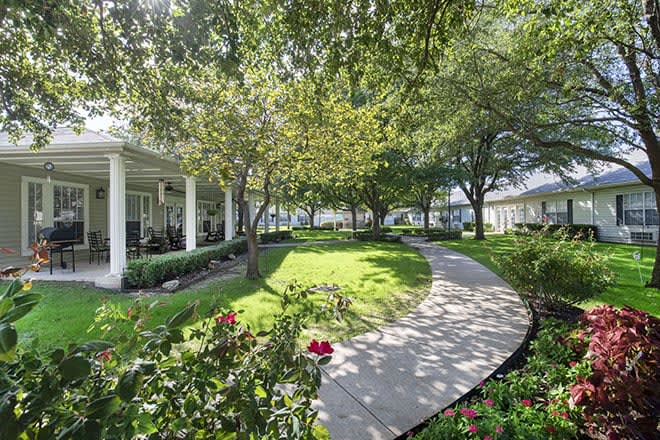 A serene garden pathway surrounded by lush greenery and flowering plants.