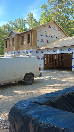 A construction site showing a partially built house with a work vehicle parked nearby.