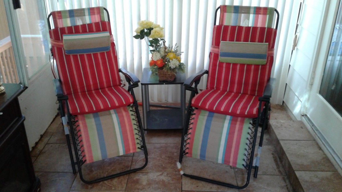 Two striped reclining chairs with a small table and floral arrangement.