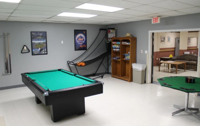 A game room featuring a pool table, a basketball hoop setup, and a bookshelf.