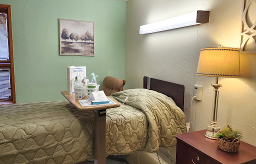 A neatly arranged hospital room featuring a patient bed, bedside table with medical supplies, and soft lighting.