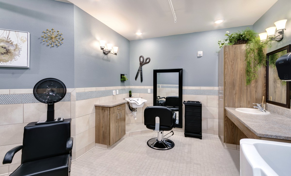 A modern hair salon featuring a styling chair, mirror, and wall-mounted scissors decor.