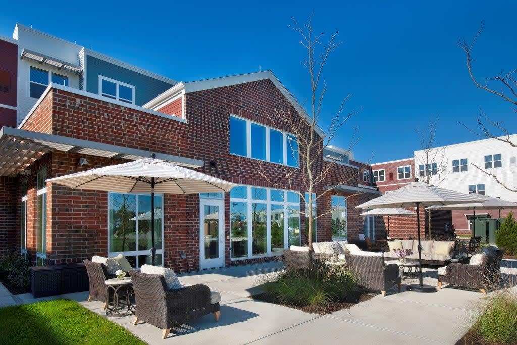 A modern building with brick exterior and outdoor seating on a sunny day.