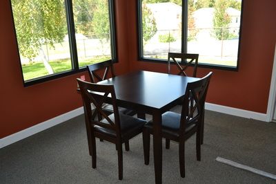 A cozy dining area with a dark wooden table and four matching chairs, surrounded by large windows.