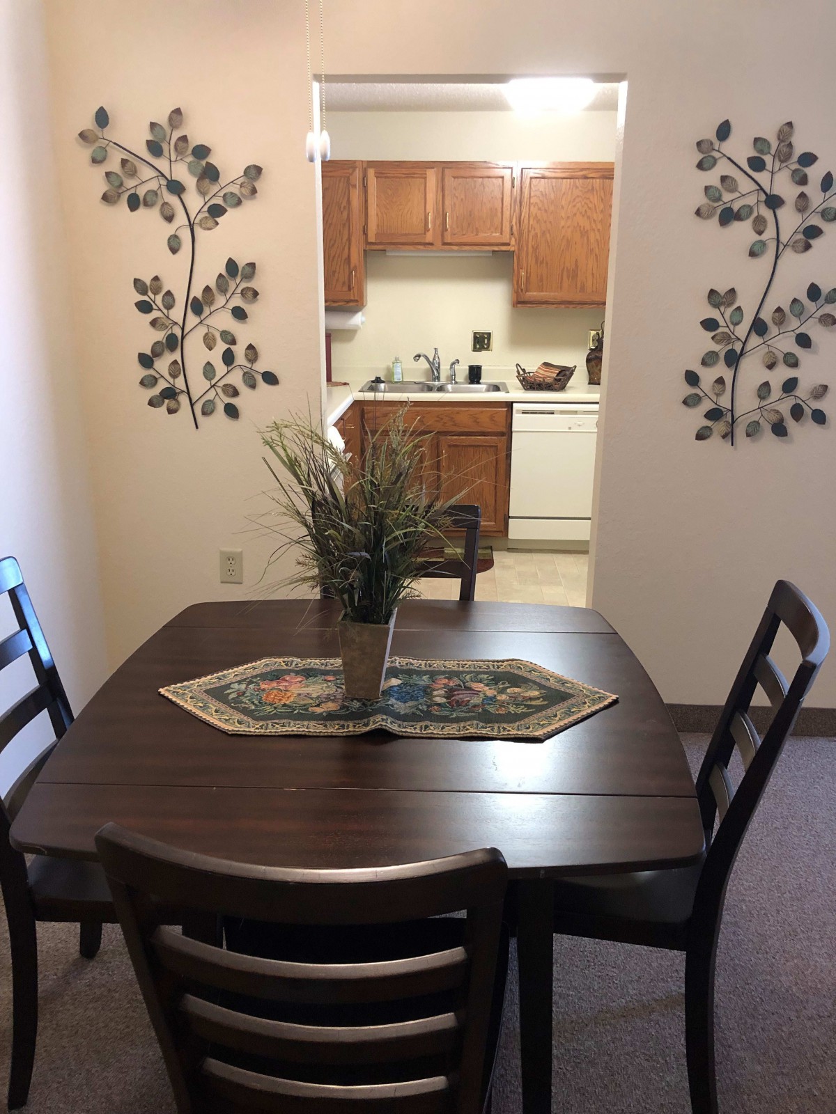 A cozy dining area with a wooden table, chairs, and kitchen in the background.
