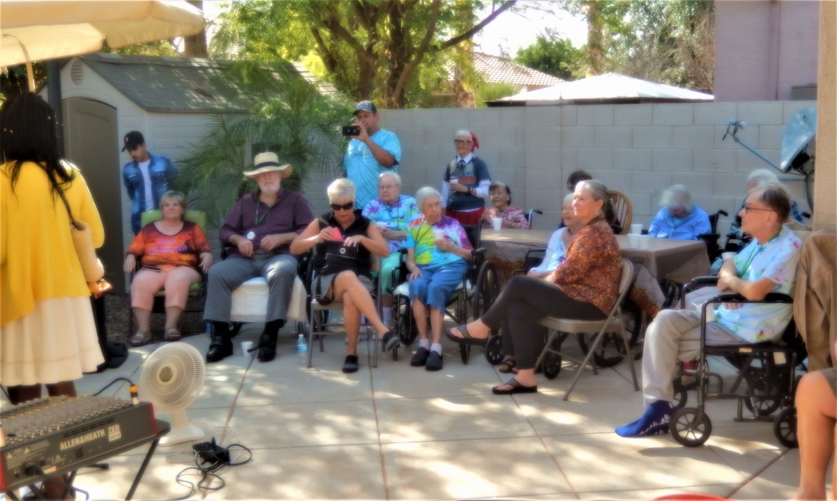 A group of elderly people sitting outside in a casual gathering.
