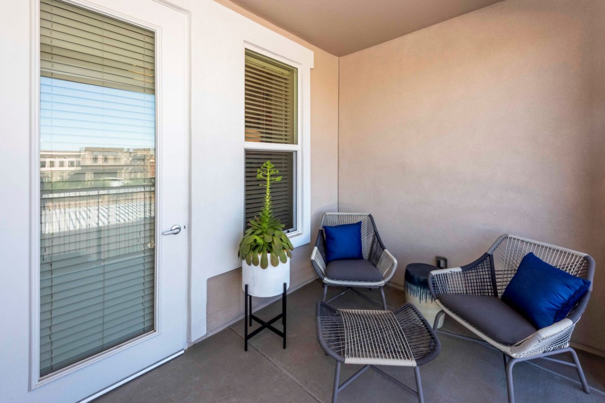 A cozy patio space with modern outdoor seating and a decorative plant.