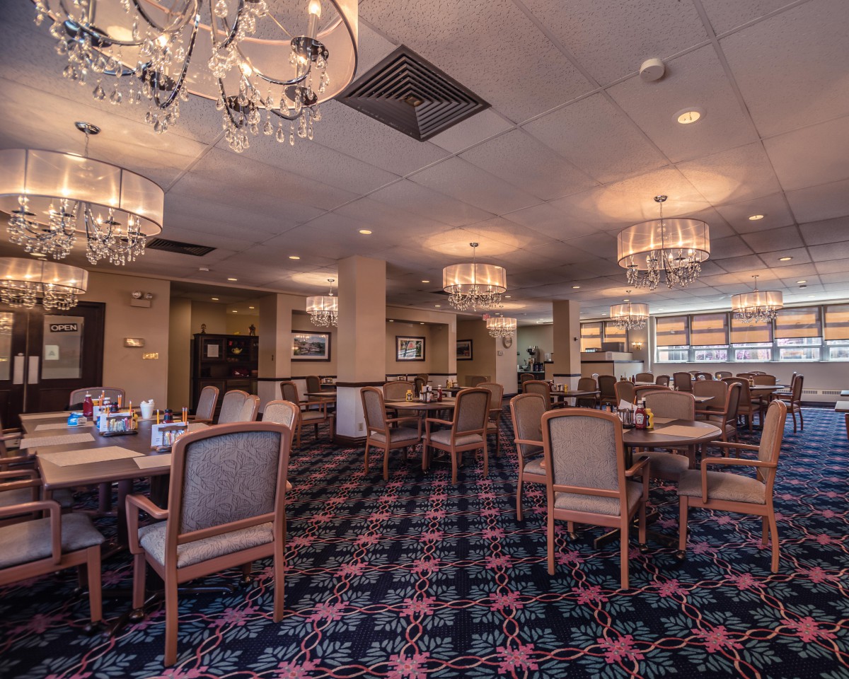 A cozy restaurant interior with elegant chandeliers and neatly arranged tables and chairs.