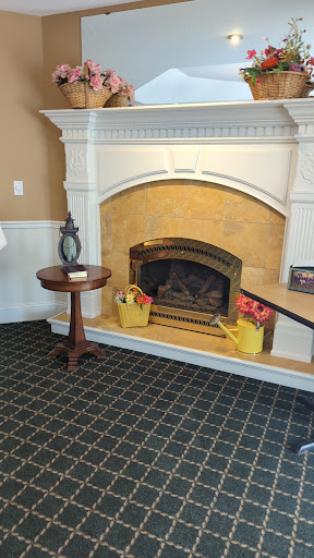 A cozy living room with a decorative fireplace and a wooden side table adorned with flowers.