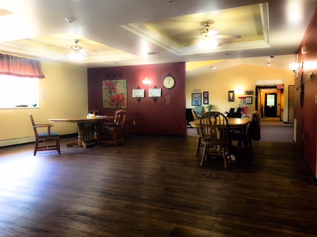 A spacious dining area with wooden tables and chairs, featuring warm lighting and ceiling fans.