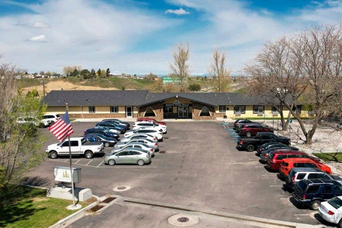 A building with a busy parking lot and an American flag flying in the foreground.