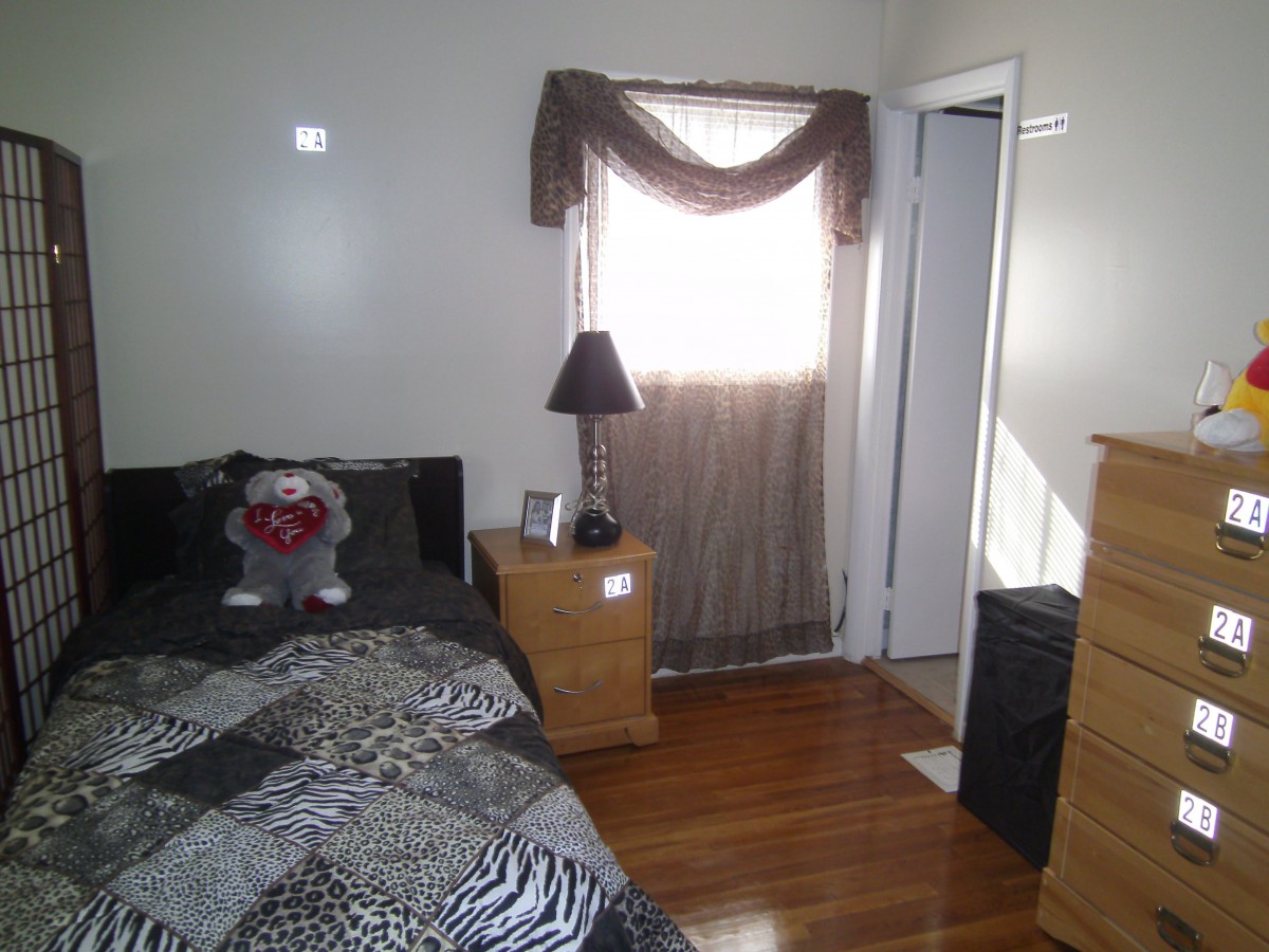 Cozy bedroom with a bed, nightstand, and window curtains.