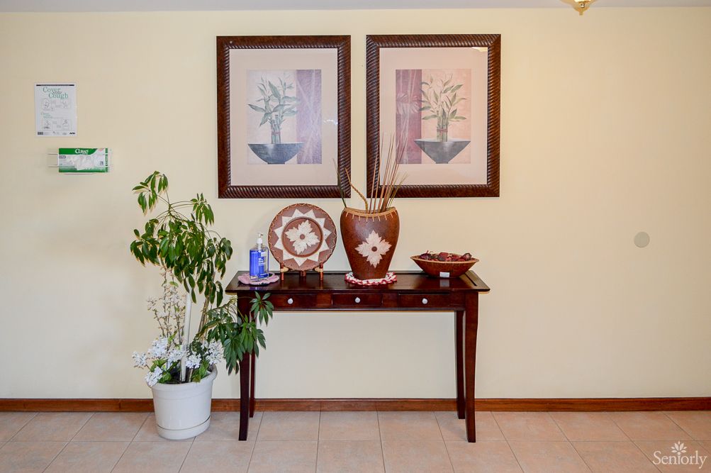 A decorated console table with artwork, a vase, and a potted plant.