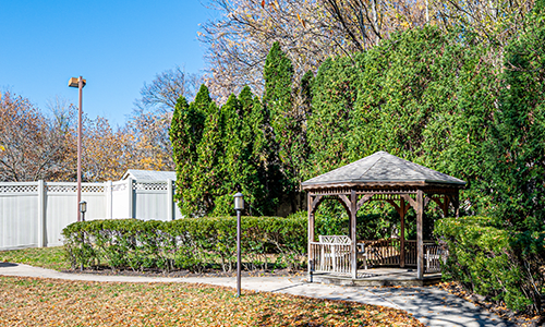 A peaceful park scene featuring a wooden gazebo surrounded by autumn foliage.