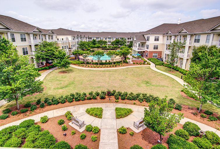 A view of an apartment complex courtyard featuring well-maintained landscaping and pathways.