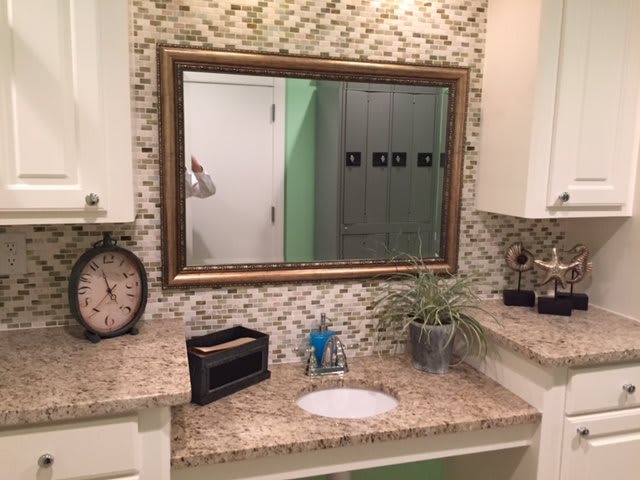 A stylish bathroom with a large mirror, decorative tiles, and elegant countertop accessories.