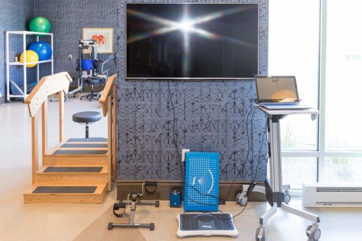 A modern fitness setup equipped with various exercise tools, a TV screen, and a laptop.