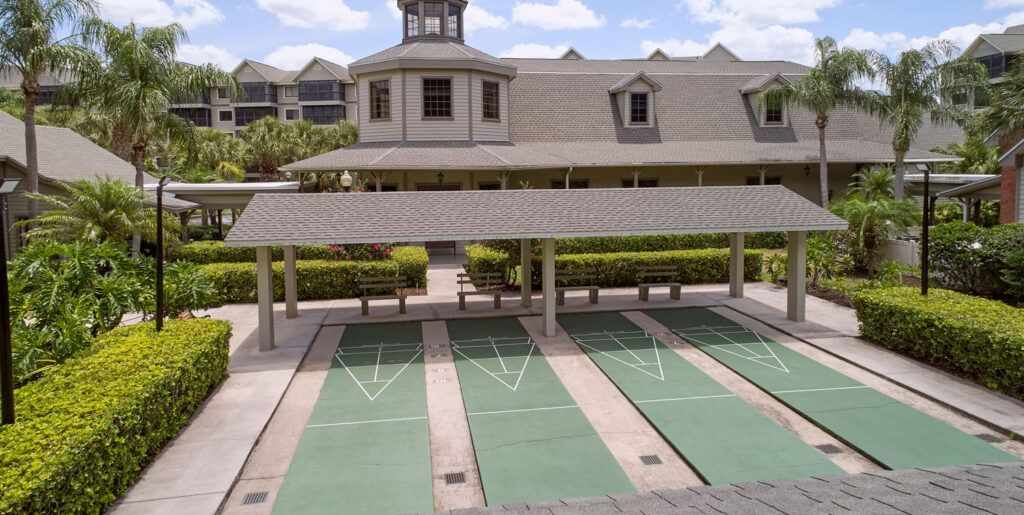 An outdoor shuffleboard court next to a building under a clear sky.