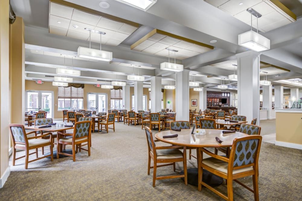 A spacious dining area with neatly arranged tables and chairs, featuring elegant lighting.