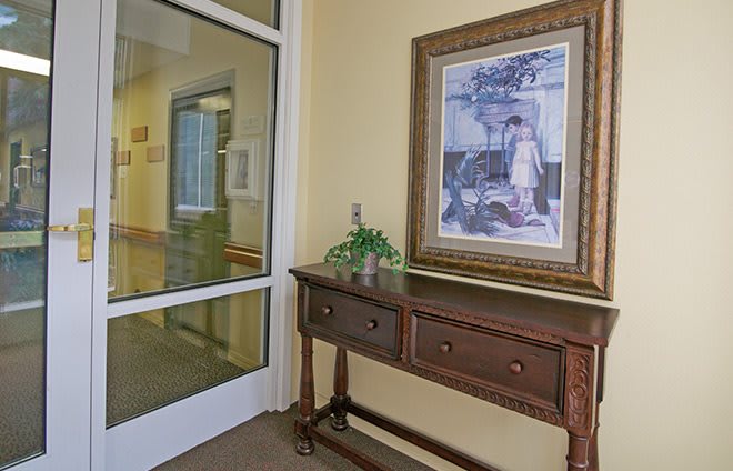 A hallway with a wooden table, decorative plant, and framed artwork on the wall.