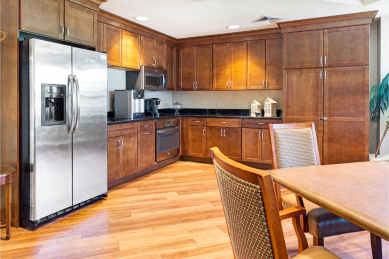 A modern kitchen with wooden cabinetry, stainless steel appliances, and a dining area.