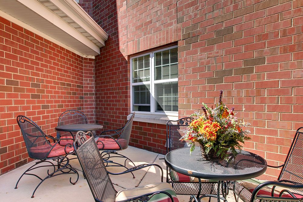 A cozy outdoor patio with wrought iron furniture and vibrant floral arrangement.