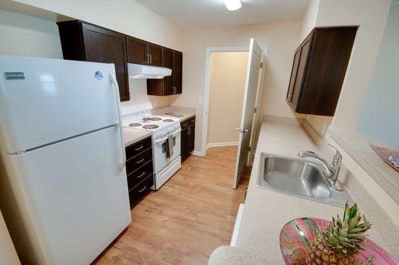 A modern apartment kitchen with dark cabinets, white appliances, and a sleek countertop.