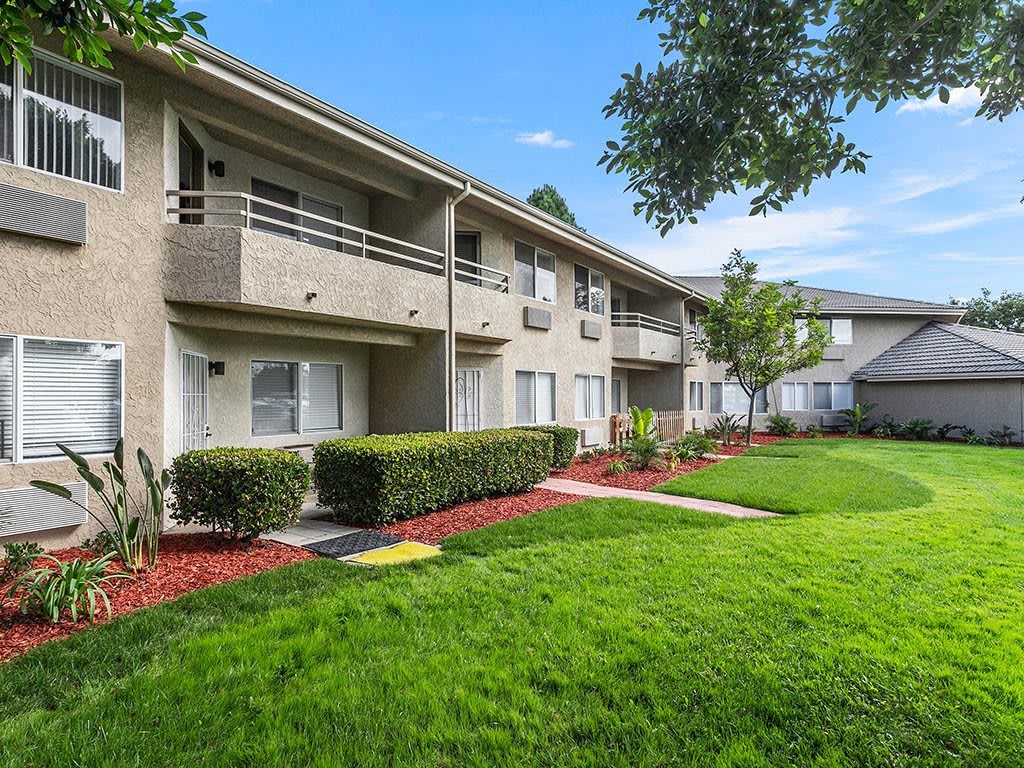 A modern apartment complex with neatly manicured lawns and lush greenery.