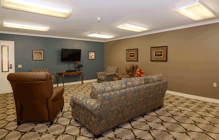 A cozy living room with sofas, chairs, a television, and framed art on the walls.