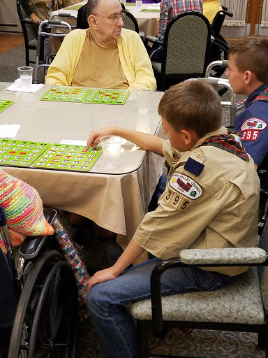 A group of children engages in a game of bingo with elderly participants, promoting intergenerational interaction.