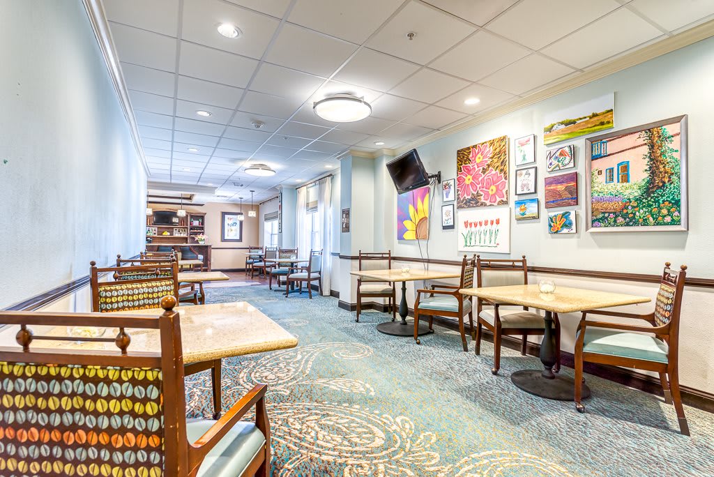 A cozy dining area with several tables and chairs, decorated with colorful artwork on the walls.