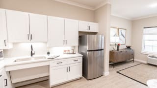 A modern kitchen with white cabinets and stainless steel fridge.