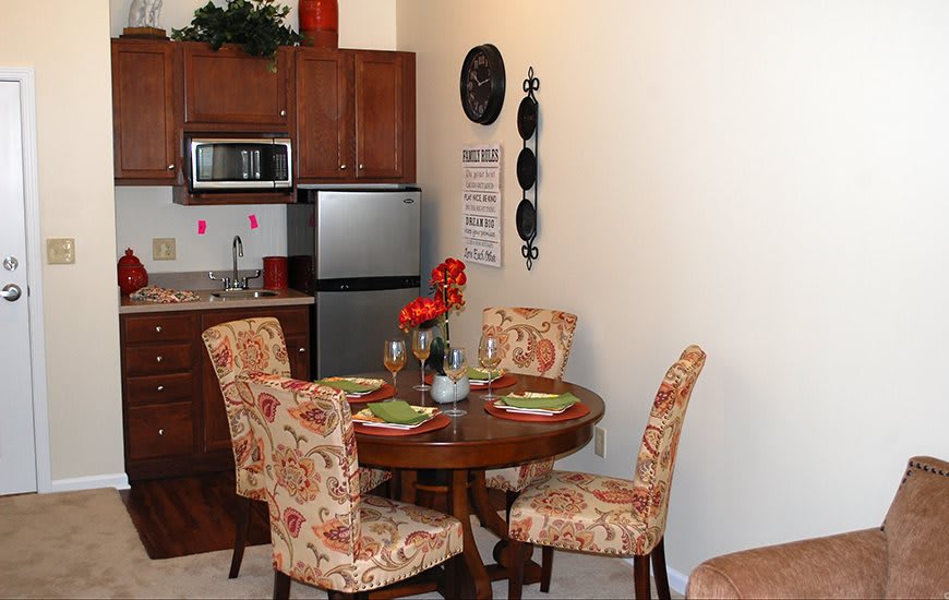 A cozy dining area with a wooden table and floral-patterned chairs next to a compact kitchen.