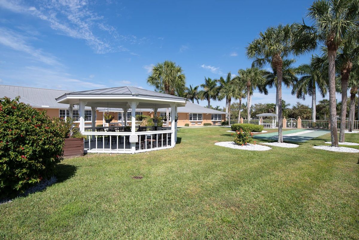 A sunny park scene featuring a gazebo surrounded by palm trees and a well-manicured lawn.
