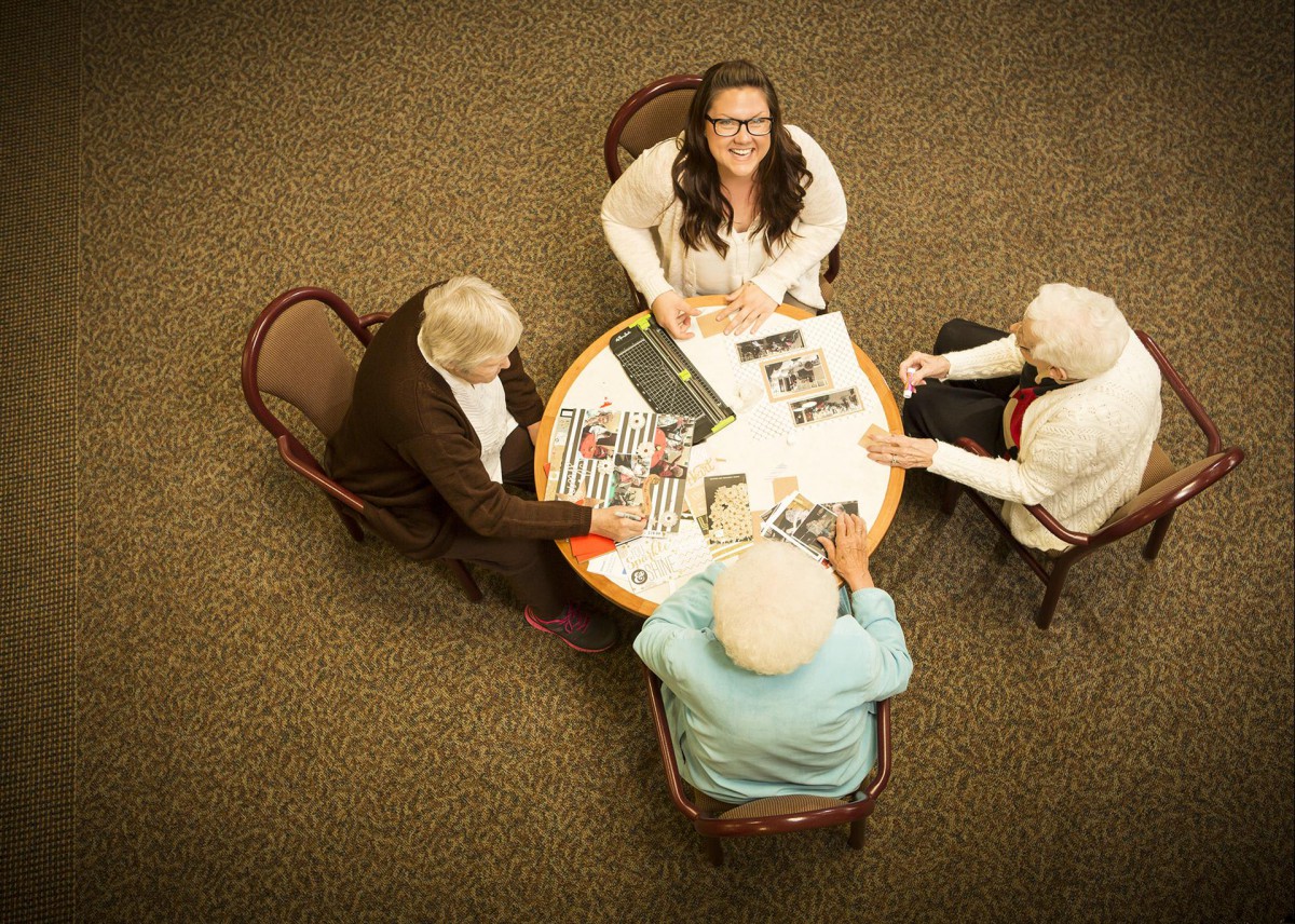 A group of four people, including seniors, sitting around a table engaged in discussion.