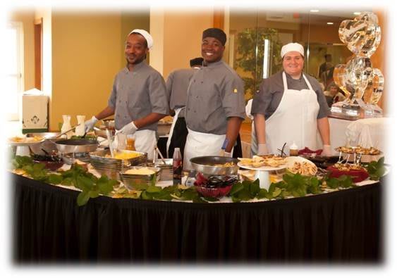 A team of chefs preparing dishes at a buffet station during a culinary event.