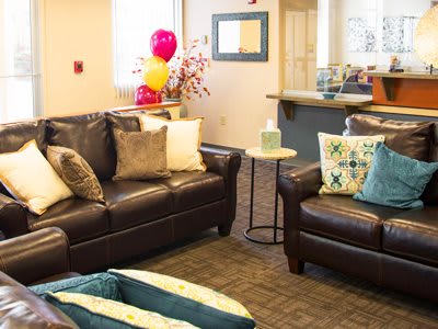 A cozy living room with leather sofas, decorative pillows, and colorful balloons.